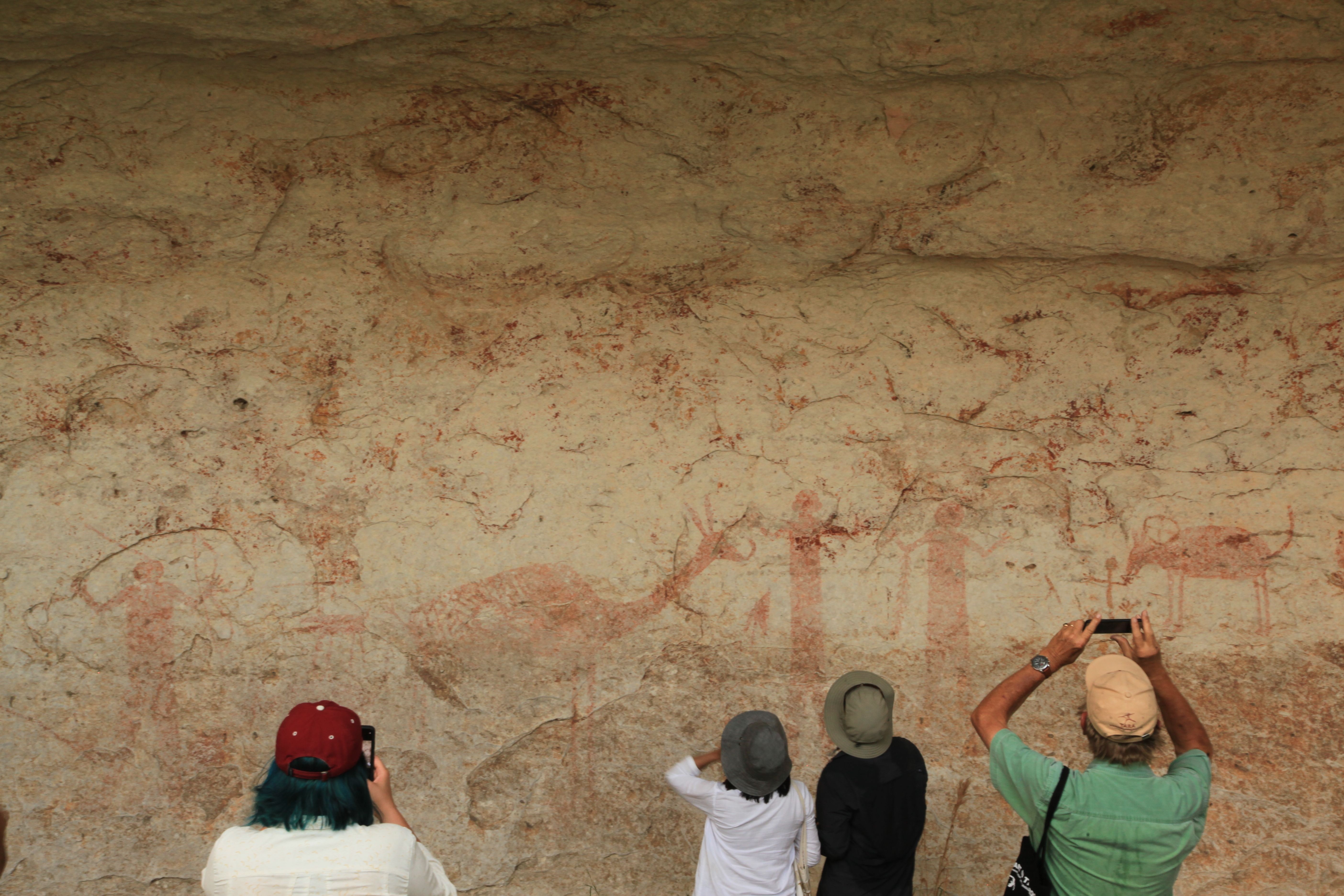people photographing a rock art mural people photographing a rock art mural